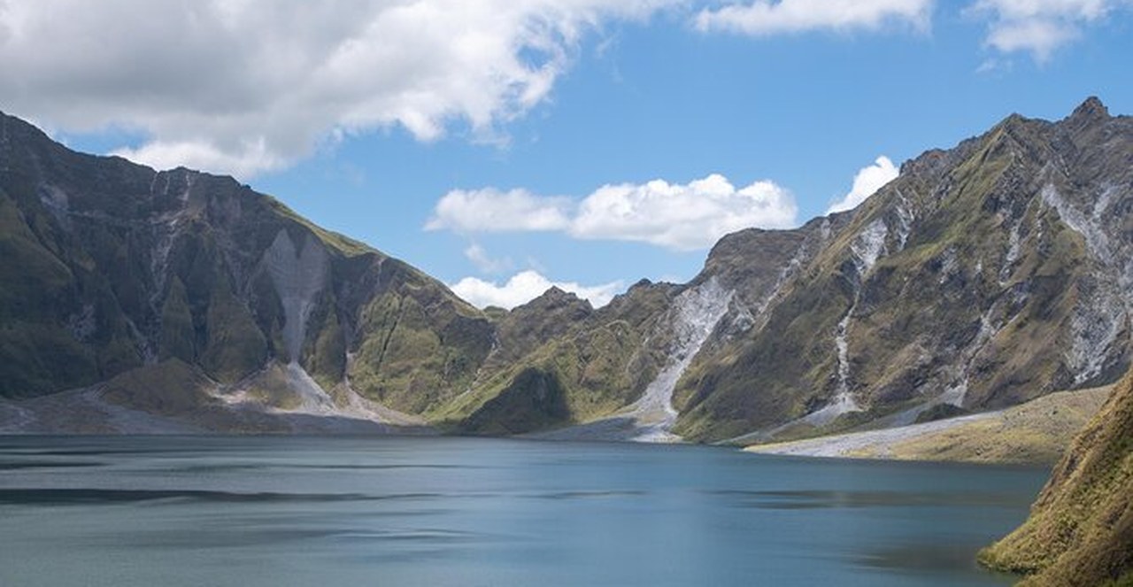 Lake Pinatubo filling the caldera, with the grey and green walls of the crater rising straight out of the water