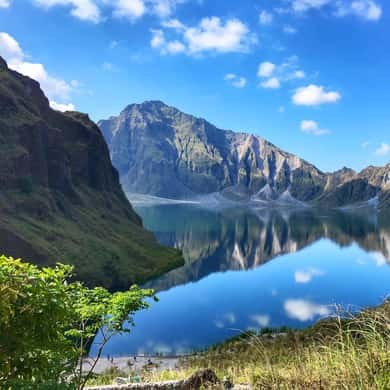 The caldera wall reflected in Lake Pinatubo on a still morning